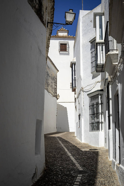 Узкая улица белых домов старого города Аркос-де-ла-Фронтера, Кадис, Андалусия, Испания с освещением средь бела дня - Фото, изображение