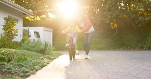 Matka, dziecko i nauka jazdy na rowerze w domu dla zabawy umiejętności, wsparcie dzieciństwa i wzrost. Szczęśliwa mama, słońce i nauka jazdy na rowerze do młodej dziewczyny na rowerze odkryty z zaufaniem, gry i rozwoju. - Materiał filmowy, wideo