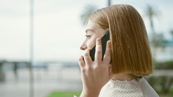 Mujer rubia joven hablando en el teléfono inteligente en la calle - Metraje, vídeo
