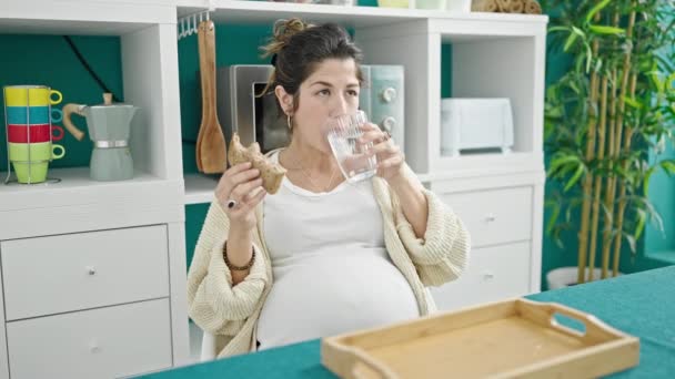 Mladá těhotná žena jíst sendvič pitnou vodu v jídelně - Záběry, video