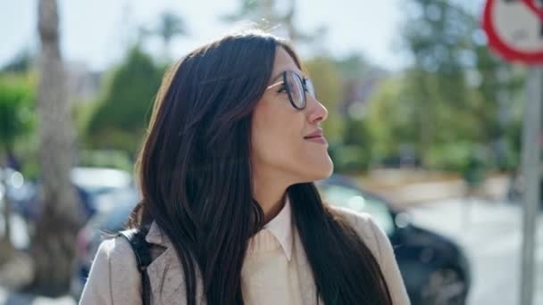 Νεαρή όμορφη ισπανόφωνη γυναίκα χαμογελά με αυτοπεποίθηση στέκεται στο πάρκο - Πλάνα, βίντεο