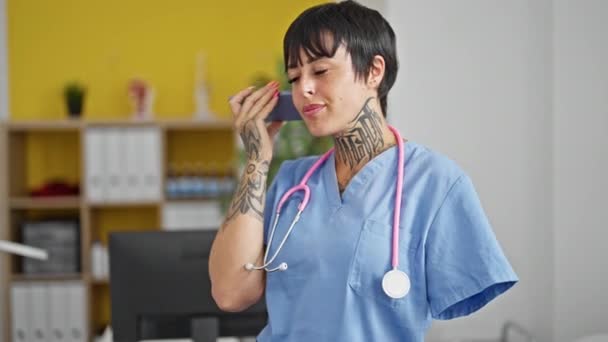 Hispánská žena s amputovanou paží lékař s úsměvem jistý poslech hlasové zprávy smartphone na klinice - Záběry, video
