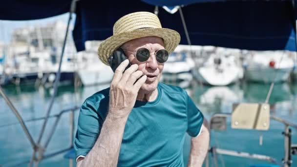 Älterer grauhaariger Tourist mit Sommermütze spricht auf Boot mit Smartphone - Filmmaterial, Video