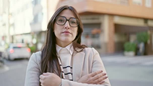Young beautiful hispanic woman standing with serious expression and arms crossed gesture at street - Materiaali, video