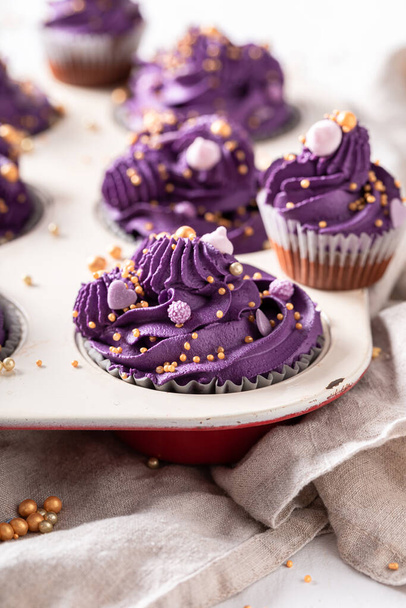 Beaux cupcakes uniques faits de crème fouettée pourpre. Dessert violet avec des paillettes dorées. - Photo, image