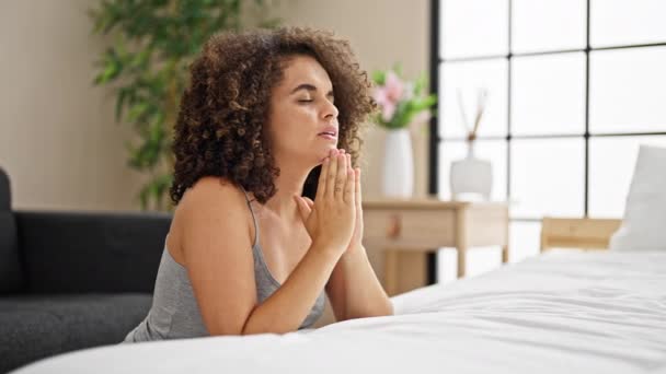 Молодая красивая латиноамериканка сидит на полу и молится в спальне - Кадры, видео