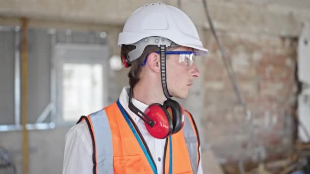 Young caucasian man architect standing with relaxed expression at construction site - Footage, Video