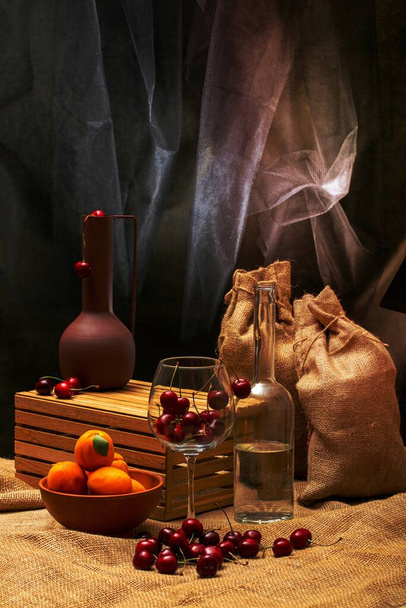 Still life with bags, ripe cherries in a glass and a bottle - Fotó, kép