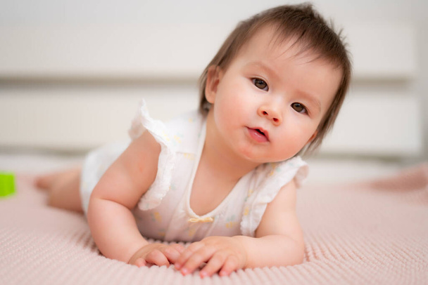 lifestyle home portrait of 9 months old mixed ethnicity Asian Caucasian baby girl playing happy and carefree on bed crawling and handling color blocks in childhood and nursery concept - Foto, Imagen
