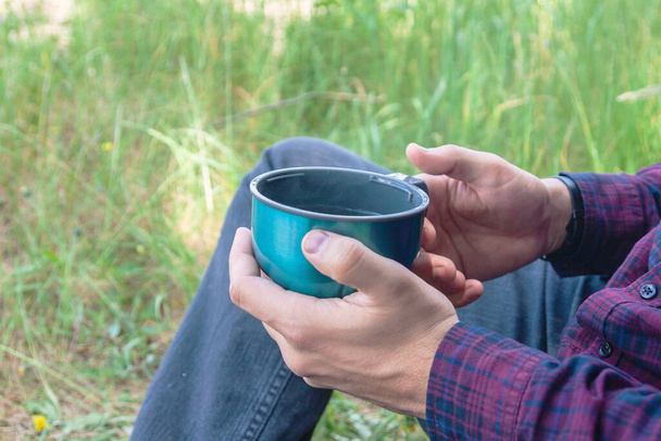 Thermo mug in human hands. Recreation in the fresh air. Active recreation in nature - Fotografie, Obrázek
