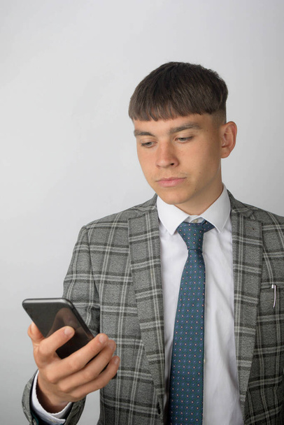 Young entrepreneur wearing a suit and tie reading a message on his phone - Fotó, kép