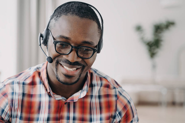 Przyjazny operator African American call center w słuchawkach i okularach konsultuje się z klientami online. Uśmiechnięty pracownik obsługi. Portret głowy. - Zdjęcie, obraz