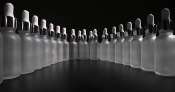 Set de frasco de suero con pipeta aislada sobre fondo negro. Primer plano del recipiente de vidrio esmerilado para el producto cosmético para el cuidado de la piel - Metraje, vídeo