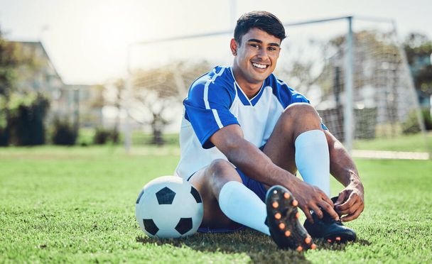 Man, soccer field and tie shoes for sports training, fitness games and performance on stadium ground. Portrait, athlete and happy football player prepare lace sneakers on grass pitch for competition. - Fotografie, Obrázek