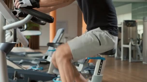 Нахилений постріл спортсмена, який використовує тренувальний велосипед у спортзалі - Кадри, відео