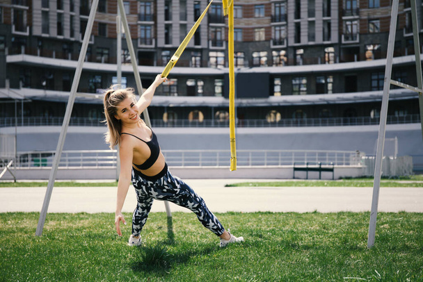 Adult woman doing fitness and sports outdoors. Healthy lifestyle, training on trx. - Foto, Bild