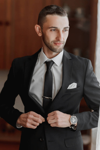 The stylish bridegroom dresses, prepares for the wedding ceremony. The groom's morning. Businessman wears a jacket, male hands closeup, groom getting ready in the morning before wedding ceremony - Zdjęcie, obraz