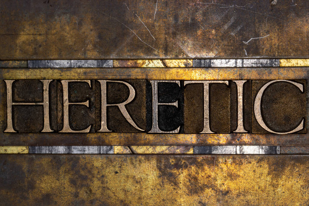 Heretic text with on grunge textured copper and gold background  - Photo, Image