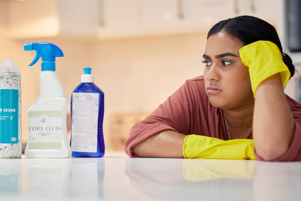Cleaning, spray bottle and frown with an annoyed woman housekeeper looking at hygiene products in the kitchen. Depression, housekeeping and supplies with a frustrated female cleaner in a home. - Φωτογραφία, εικόνα