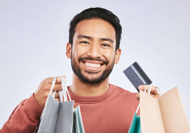 Shopping bag, portrait and man with happiness, credit card and smile for retail fashion spree, sales or Black Friday deal. Promotion face, studio payment and happy male customer on white background. - Valokuva, kuva