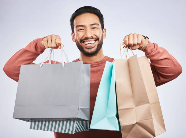 Shopping bag, studio portrait and happy man customer or client with retail product, gift or fashion spree choice. Boutique discount deal, market present and excited person smile on white background. - Foto, afbeelding