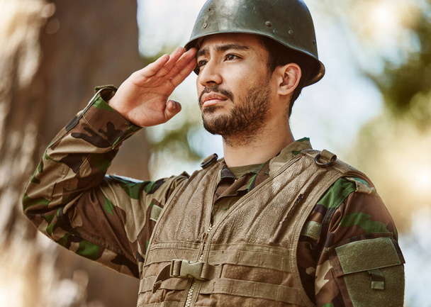 Żołnierz, wojsko i człowiek salutują w naturze za służbę, ochronę i szkolenie bojowe na świeżym powietrzu. Wojna, wojsko narodowe i mężczyzna na stanowisku dla weteranów honoru, powitania i oficjalnych obowiązków w lesie. - Zdjęcie, obraz