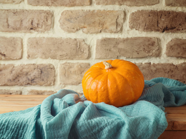 Autumn concept with orange pumpkin on wooden table over brick wall background. Thanksgiving greeting card - Foto, Imagem