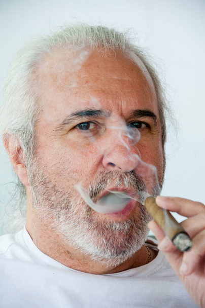 Іспаномовний старший чоловік насолоджується кубинською сигарою. старий іспаномовний чоловік вдарив кубинську сигару. Кубинська сигара. палити старого іспаномовного чоловіка. пенсійний спосіб життя. іспаномовний старий палить кубинську сигару. багаті і гладкі смаки. - Фото, зображення