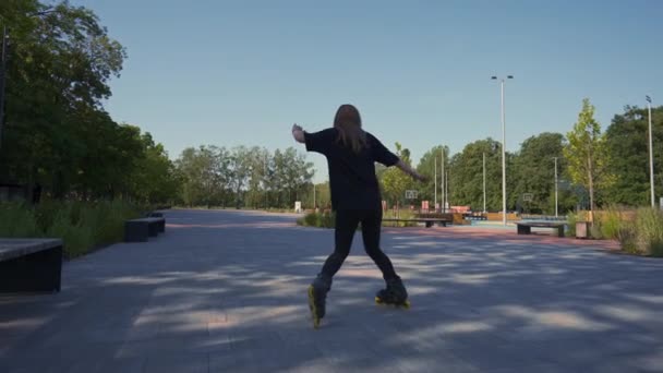 chica deportiva paseos patines en el parque en el fondo de la ciudad chica activa en disfruta de patinaje lección calle concepto de deportes de calle - Metraje, vídeo