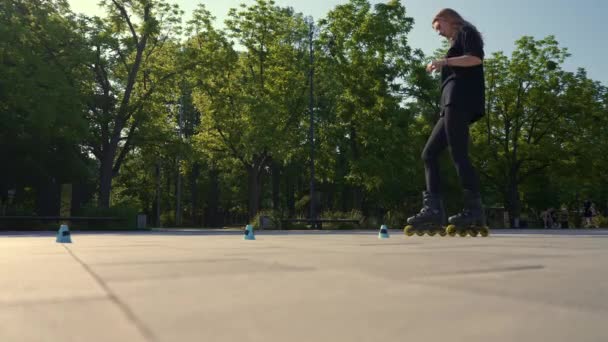 sportowa dziewczyna ćwicząca sztuczki na wrotkach w parku tło miasta korzystających na wrotkach lekcja jazdy na wrotkach z szyszkami zbliżenie street sport - Materiał filmowy, wideo