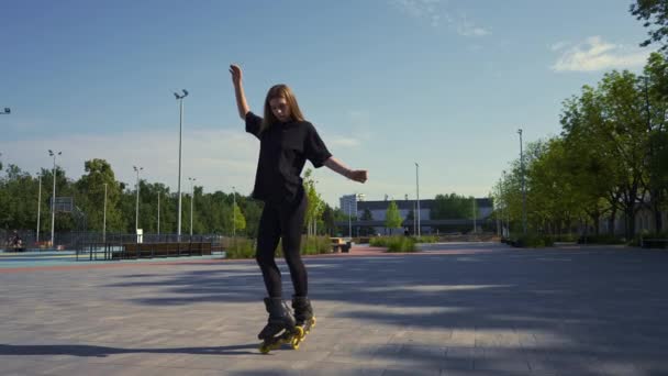 menina esportiva monta patins no parque no fundo da cidade Menina ativa em gosta de andar de skate lição rua esportes conceito - Filmagem, Vídeo