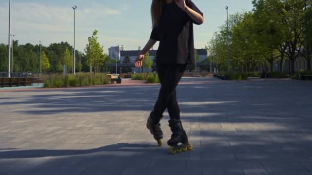 urheilullinen tyttö ratsastaa rullaluistimet puistossa kaupungin taustalla Aktiivinen tyttö nauttii rullaluistelu oppitunti Street urheilu käsite - Materiaali, video