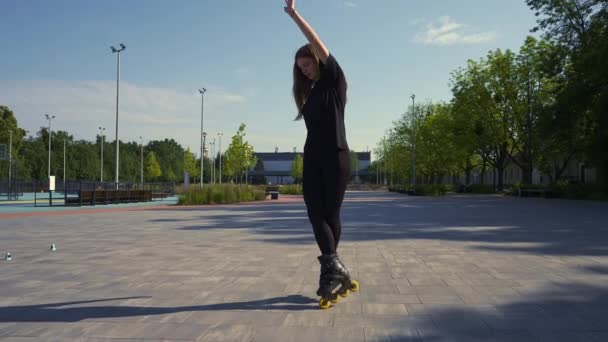 menina esportiva monta patins no parque no fundo da cidade Menina ativa em gosta de andar de skate lição rua esportes conceito - Filmagem, Vídeo