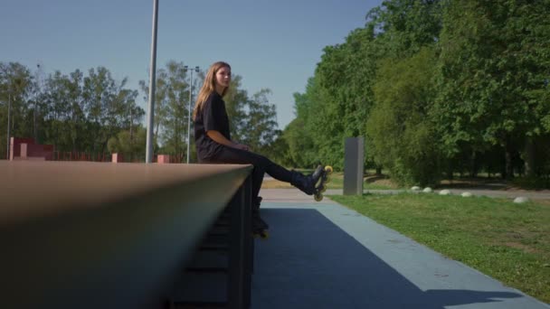 sportovní dívka po bruslení spočívá na sportovním hřišti zamyšlený šťastný s pouliční sportovní lekce - Záběry, video