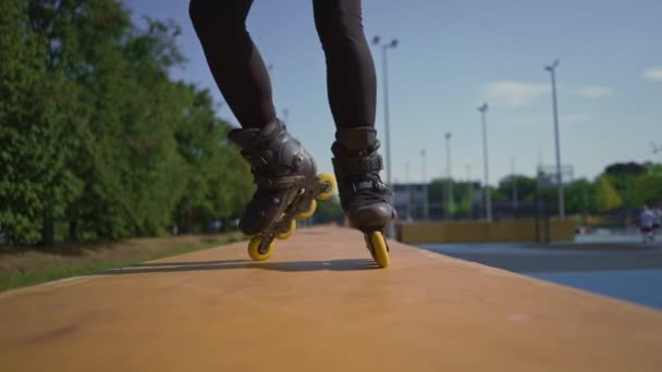 sportowa dziewczyna ćwiczy sztuczki na wrotkach w parku tło miasta korzystających na wrotkach lekcja jazdy na wrotkach zbliżenie nogi ulica sport - Materiał filmowy, wideo