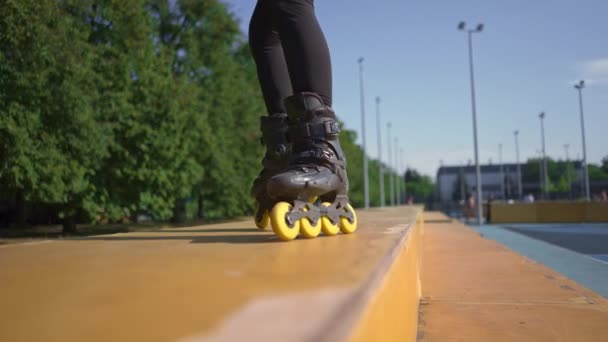 sportovní dívka cvičení triky na kolečkových bruslích v parku město pozadí těší kolečkových bruslích lekce zblízka nohy street sport - Záběry, video