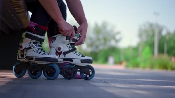 fiatal hipster lány felvesz görkorcsolya park előtt elkezd korcsolyázni utca extrém sport közelkép lábak - Felvétel, videó