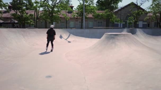 junge, erfahrene Rollschuhläuferin, die auf der Rampe im Skatepark im Freien ihre Tricks und Techniken des Rollschuhwettbewerbs übt - Filmmaterial, Video