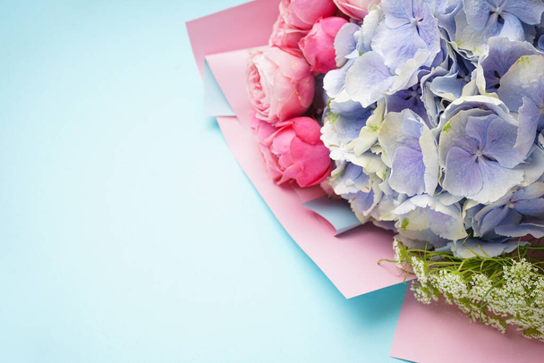 Ramo de rosas peonias con hortensias sobre fondo azul, espacio para texto. Puesta plana. - Foto, imagen