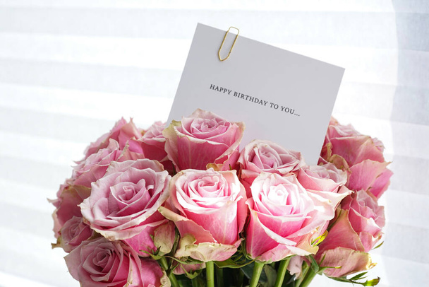 Bouquet von schönen rosa Rosen mit einer Grußkarte, Ansicht von oben. Nahaufnahme. - Foto, Bild