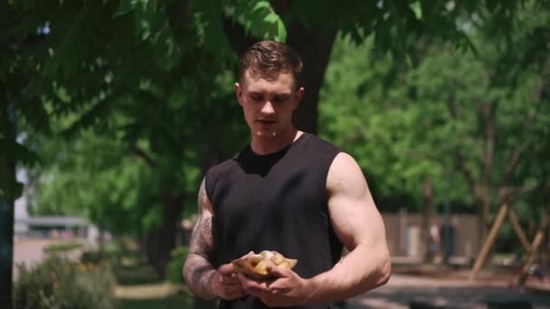 jovem desportista depois de treinar segurando doces donuts em suas mãos hesita se comê-los junk food - Filmagem, Vídeo