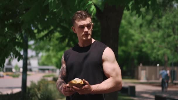 mladý sportovec po tréninku drží sladké koblihy v rukou váhá, zda jíst je nezdravé jídlo - Záběry, video