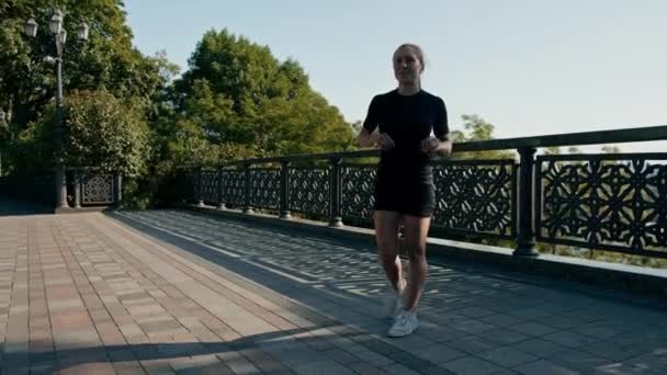 Fitness jonge sportvrouw meisje in de ochtend doen warming-up been oefeningen voor de training op straat in de stad op brug Sport gezondheid - Video