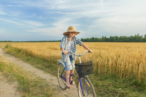 Хлопчик-підліток їде на велосипеді по сільській дорозі
 - Фото, зображення