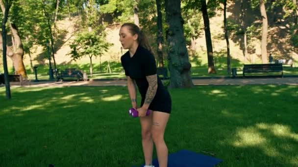 retrato de una joven deportista satisfecha haciendo ejercicios con pesas al aire libre durante un entrenamiento en el parque concepto de estilo de vida saludable - Metraje, vídeo