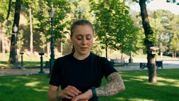Portrét mladé sportovkyně, která kontroluje čas a puls na chytrých hodinkách po tréninku v konceptu zdravého životního stylu parku - Záběry, video
