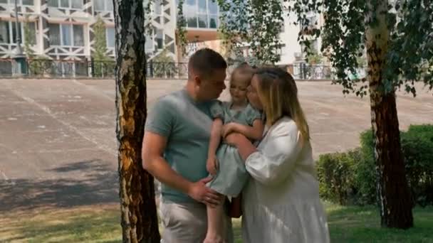 Portrét usmívající se mladé rodiny maminka táta a malá dcera rodina na procházce v parku šťastné dětství - Záběry, video
