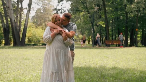 portret zakochanej pary mężczyzna i ciężarna kobieta przytulają mężczyznę całują jego żonę czekając na nowy dodatek do szczęśliwej rodziny - Materiał filmowy, wideo
