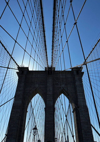 Cables que conducen a una torre en el puente de Brooklyn contra un cielo azul - Foto, imagen
