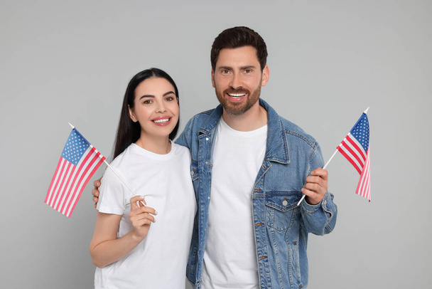 4th of July - Independence Day of USA. Happy couple with American flags on grey background - Foto, afbeelding